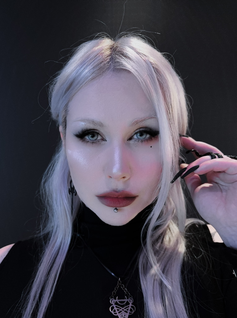 Anomalyda (Ida-Emilia Kaukonen), silver-white hair, dark clothing, cool studio light.